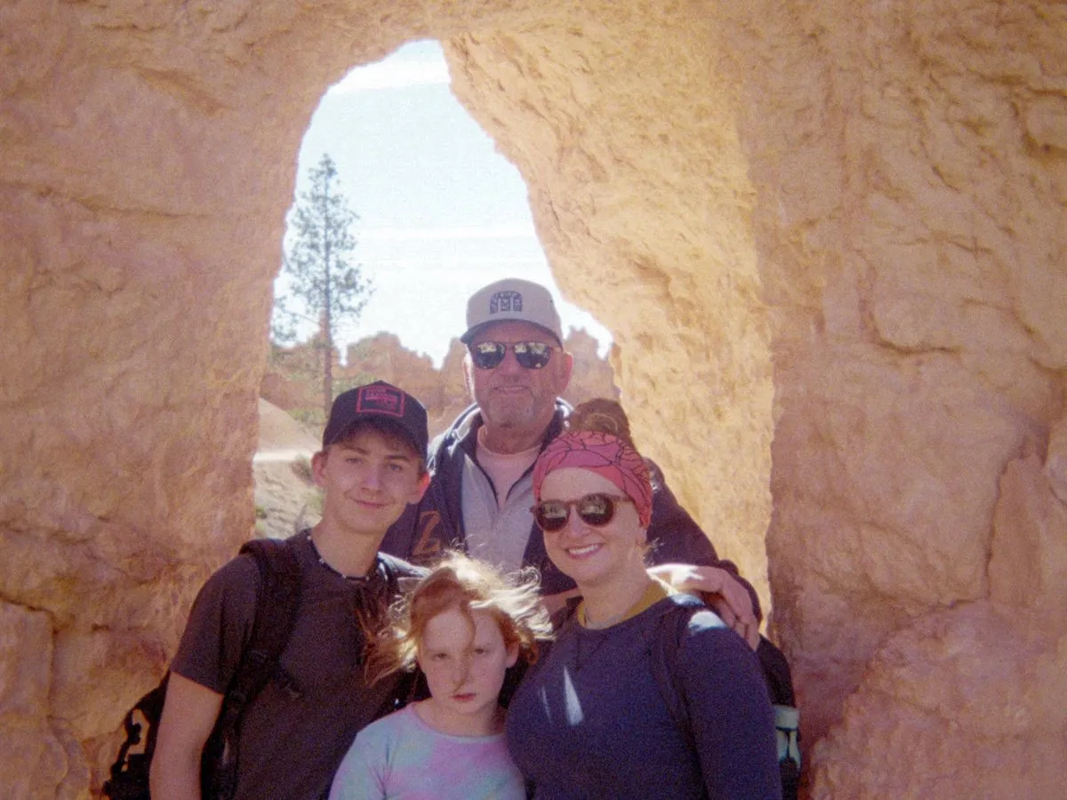 Hikers standing inside a carved sandstone arch at the sand caves outside Kanab, Utah.